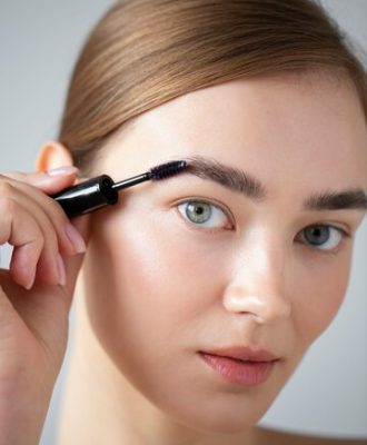 portrait-beautiful-woman-with-clear-skin-brushing-her-eyebrows_23-2149207873